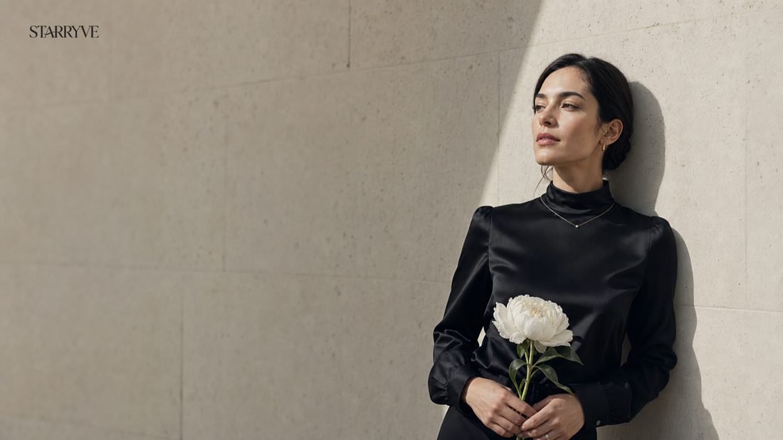 Woman in black holding a white flower in a minimalist stone interior