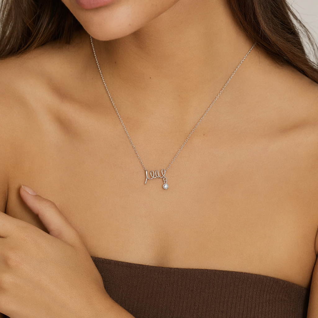 Woman wearing the silver scripted love necklace with a light top