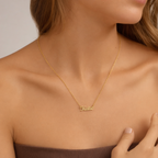 Woman wearing the gold custom name necklace with a dark top