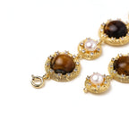 Close-up of a tiger's eye and pearl medallion on the bracelet