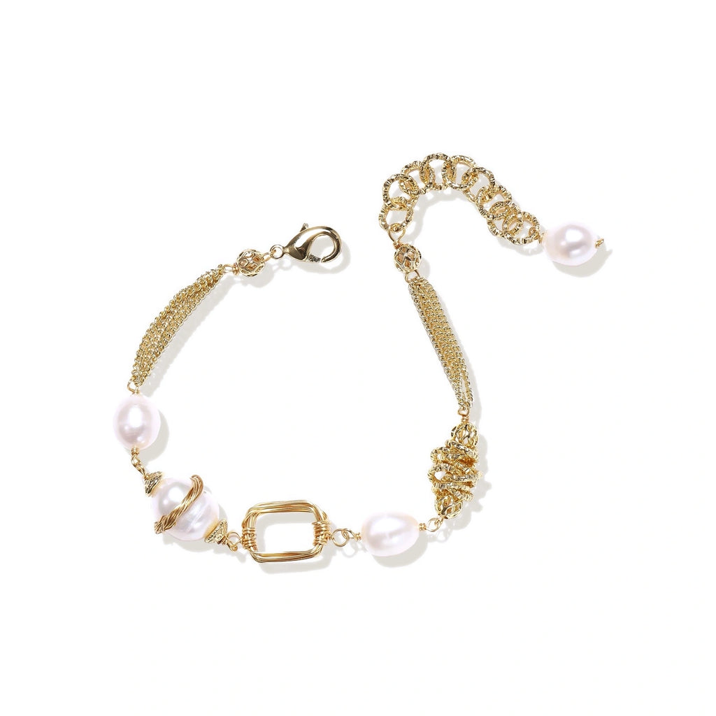 Woman wearing the golden pearl bracelet stacked with other jewelry