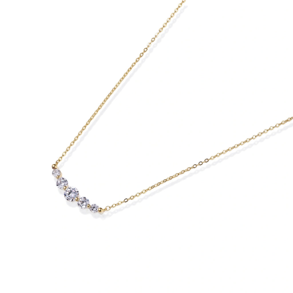 Flat lay of the golden arc necklace on a white background