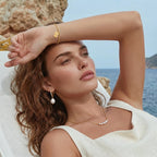 Woman wearing the golden arc necklace with a light off-shoulder top