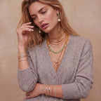 Woman wearing the emerald garden necklace layered with other gold necklaces