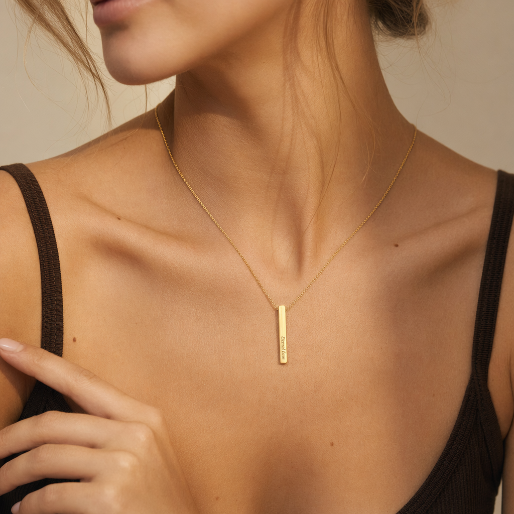Close-up of the gold engraved bar pendant worn at the collarbone