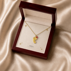 Gold baby feet birthstone necklace displayed in a mahogany LED luxury gift box
