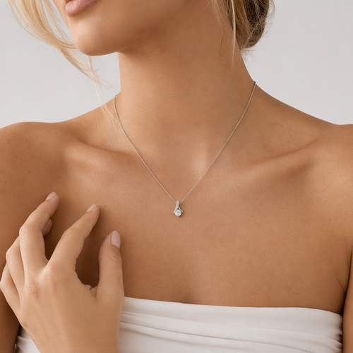 Woman wearing the white gold ribbon pendant necklace with a light top