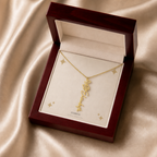 Gold flower name necklace with the May lily of the valley birth flower, shown in a mahogany LED luxury gift box