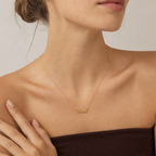 Close-up of the gold custom name necklace at the neckline