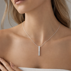 Woman wearing the silver 4-sided bar necklace with a white top