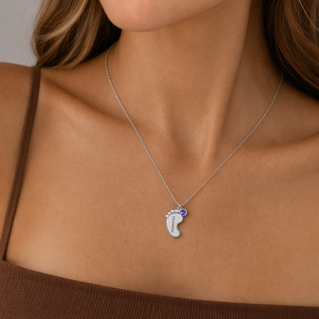 Close-up of the silver baby feet birthstone necklace at the neckline