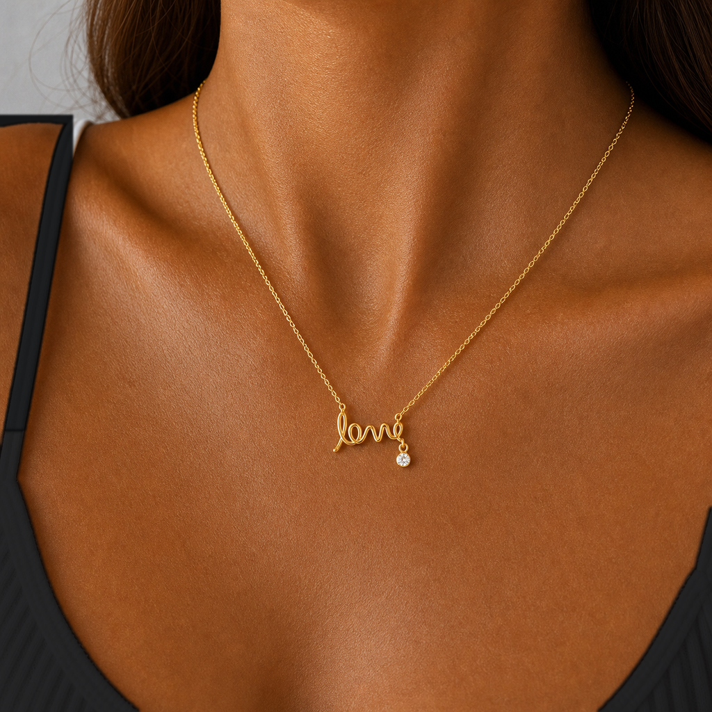Close-up of the gold scripted love necklace worn at the neckline