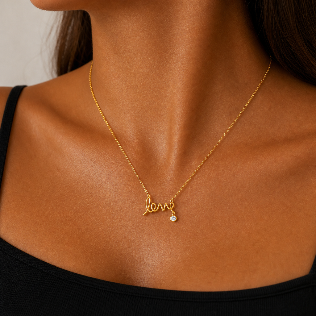 Woman wearing the gold scripted love necklace with a black top